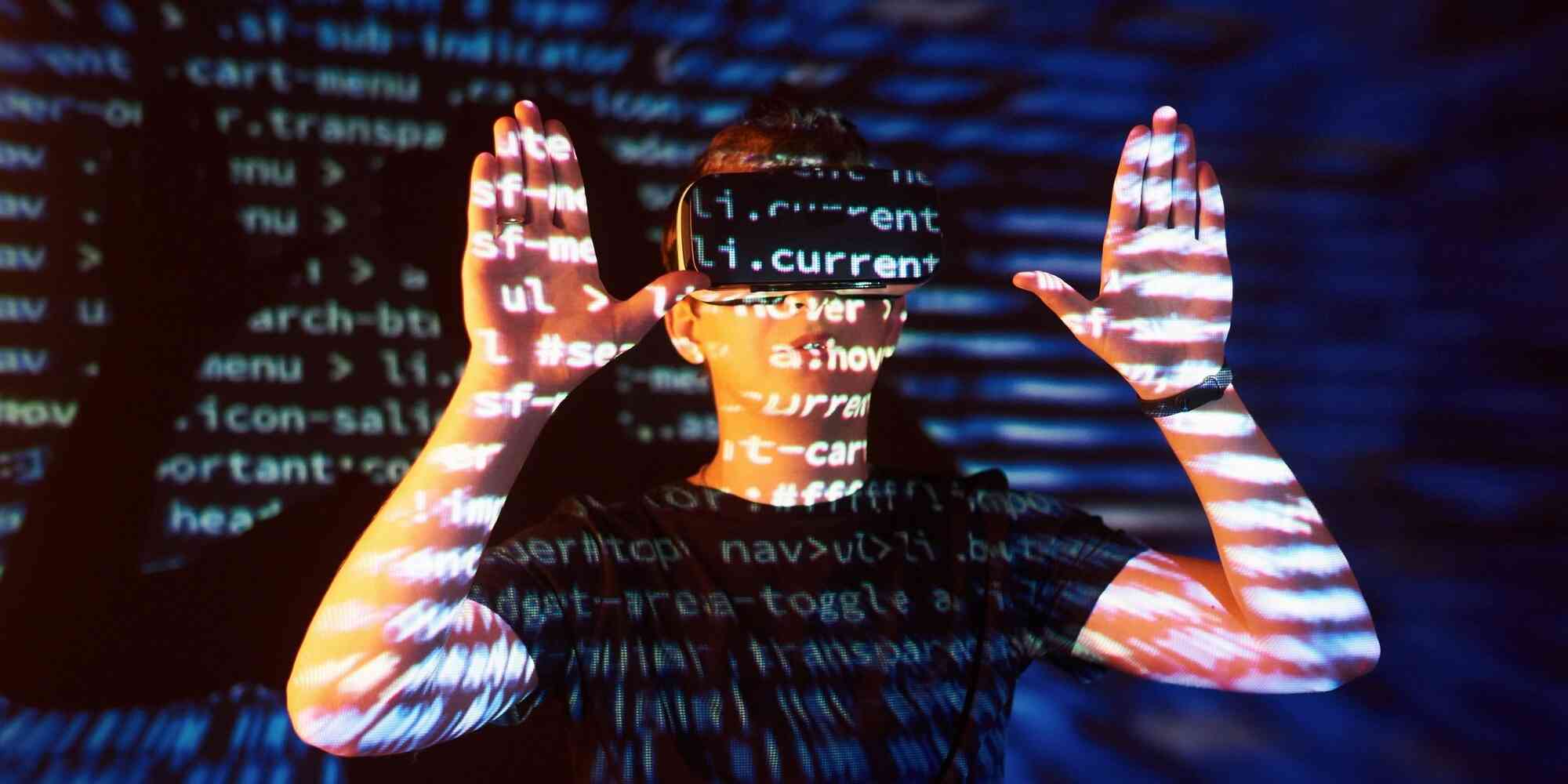 一个戴着虚拟现实眼镜的人他的脸被投影在屏幕上。