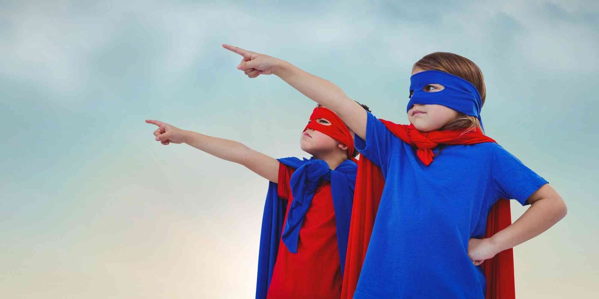 图中两个穿着超级英雄服装的小朋友，手拉着手望着天空。