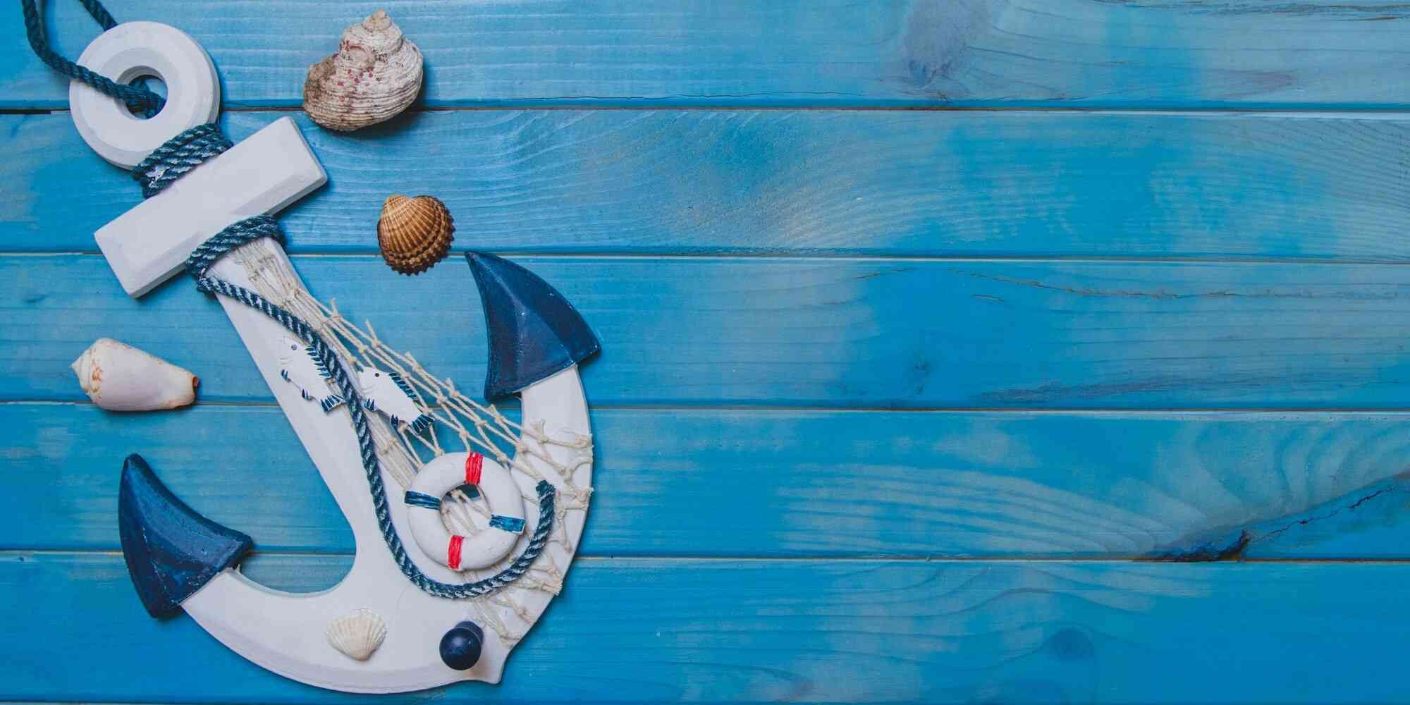 锚和贝壳的装饰品，挂在蓝色木板上。它代表着海洋中的力量、稳定和安全的象征。锚是船在航行时用来控制方向的工具；而贝壳则象征着海洋中的生物，它们被广泛用于装饰各种物品或艺术品。