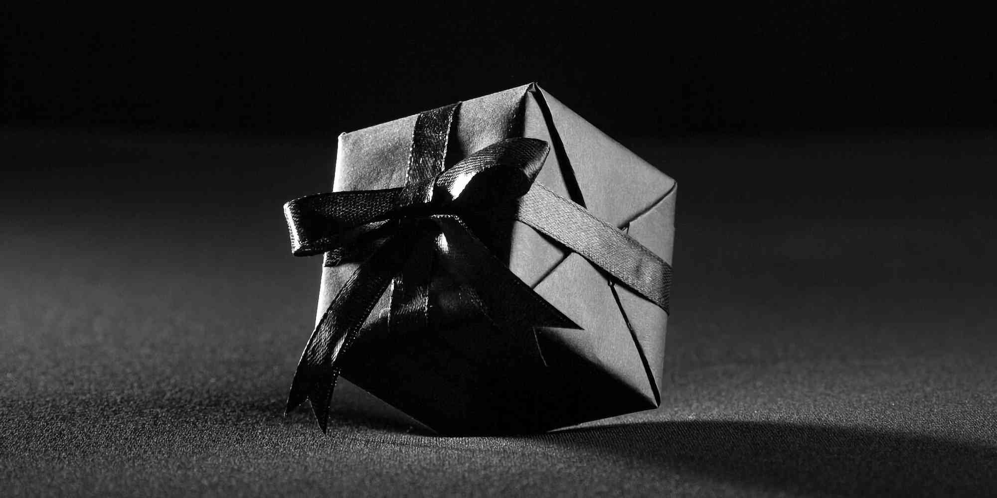 黑色盒子，绑着一条黑丝带。它静静地躺在黑色的背景上，似乎被遗忘了。它散发着神秘的气息，让人不禁想要靠近去探寻它的内心。它或许有着令人难以捉摸的故事，或者只是一个简单的礼物，但它却承载着一份情感和祝福。